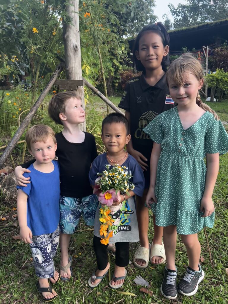 A group of local Thai children and foreign children smiling together, demonstrating cross-cultural exchange in Umphang, Thailand.