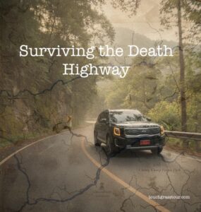 Winding road of Thailand's Umphang Highway (Death Highway) curving through misty jungle mountains.