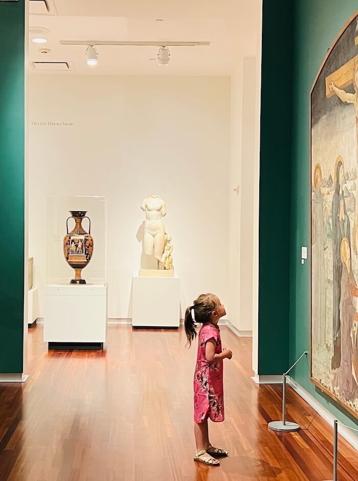 This card shows a young girl looking at a painting in a museum.