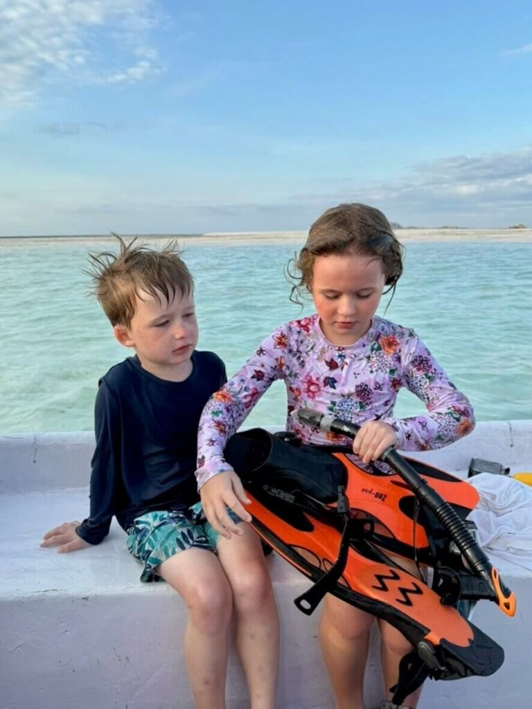 Kids on a boat trip holding snorkeling gear fins ready for water in Labuan Bajo