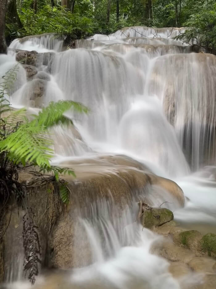 Limestone tiers of Phu Kaeng Waterfall in Doi Luang National Park, Chiang Rai. Long exposure photo shows silky water flow and lush ferns.