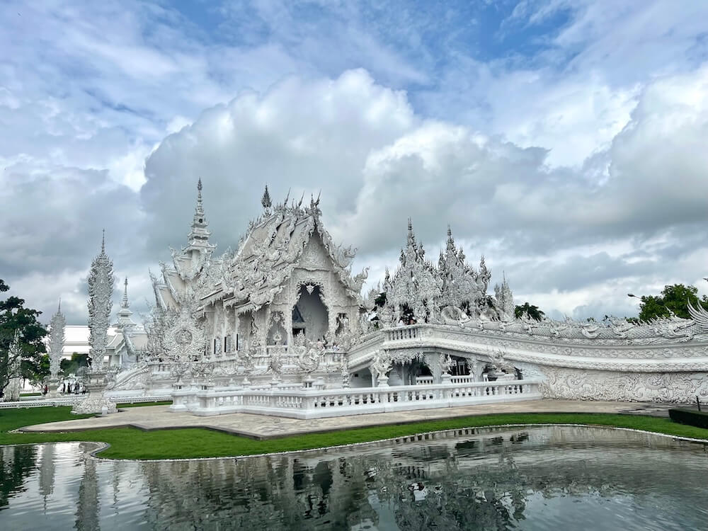 Wat Rong Khun White Temple Chiang Rai Thailand under a cloudy sky.