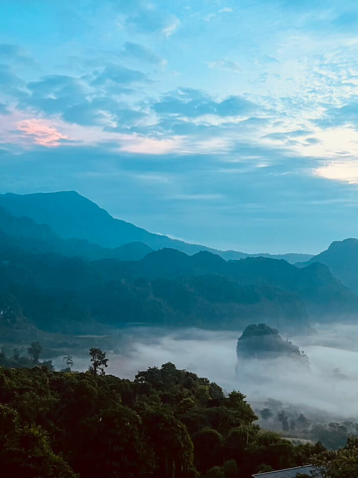 Blue Hour Sea of Clouds Phu Langka A vertical view of the Phu Langka valley during the blue hour, featuring the dark silhouette of the Pha Chang Noi karst surrounded by a low-lying sea of white mist.