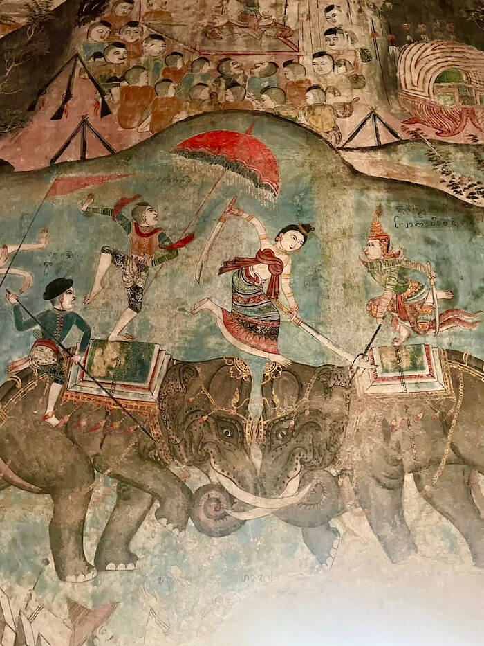 An ancient temple mural at Wat Nong Bua depicting warriors on elephants engaged in a dramatic battle.