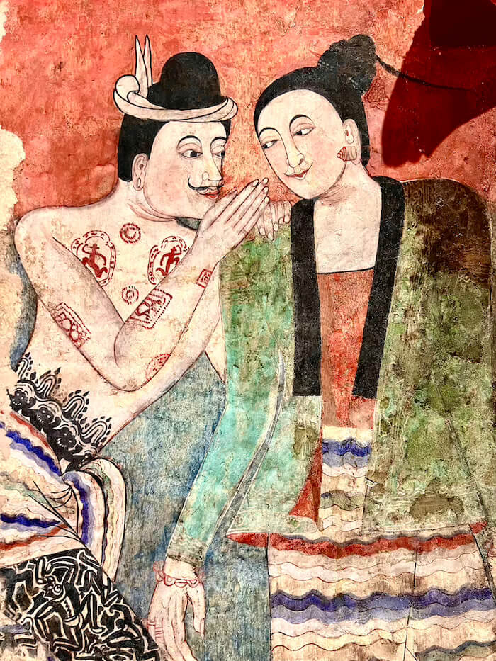 The famous "Whisper of Love" mural at Wat Phu Min in Nan, Thailand, depicting a tattooed Tai Lue man whispering into a woman's ear.
