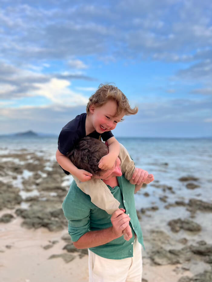 Low Tide Adventures on Koh Bulon A father carrying his young son on his shoulders while walking along the rocky shoreline of Koh Bulon Lae at low tide.