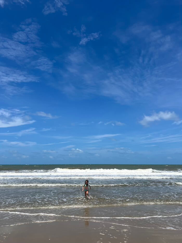 Family Fun on Mae Ramphueng Beach A young girl running through the shallow waves on the long, golden sands of Mae Ramphueng Beach in Rayong, Thailand.