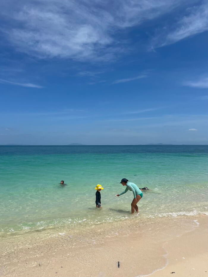 Crystal Waters of Lao Liang South A woman and children swimming in crystal-clear turquoise water at Koh Lao Liang South beach under a bright blue sky.