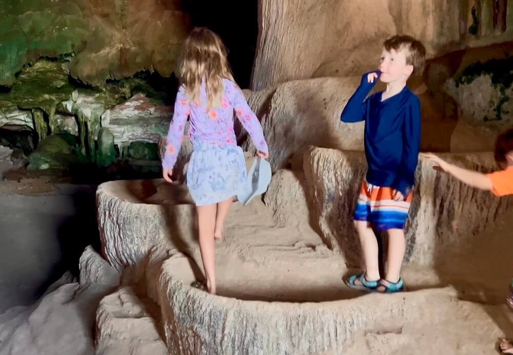 Children exploring crystalline rimstone pools inside the Ice Cream Cave in Phang Nga Bay, Thailand.