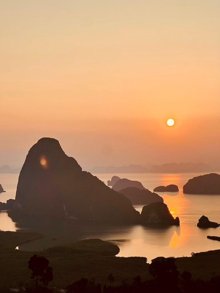 A breathtaking golden sunrise over the iconic limestone karst islands of Phang Nga Bay, viewed from Samet Nangshe Viewpoint in Thailand.
