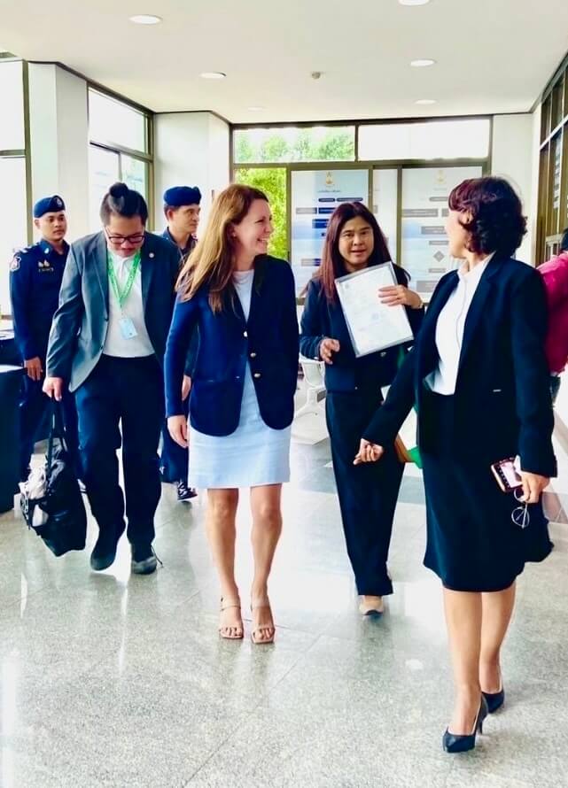 A group of business professionals and officials walking through a modern building hallway during an official visit.