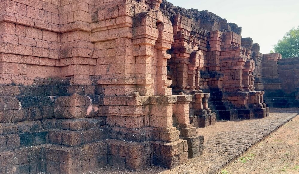 The weathered reddish-black laterite stone block base of Khao Khlang Nai at Si Thep Historical Park.