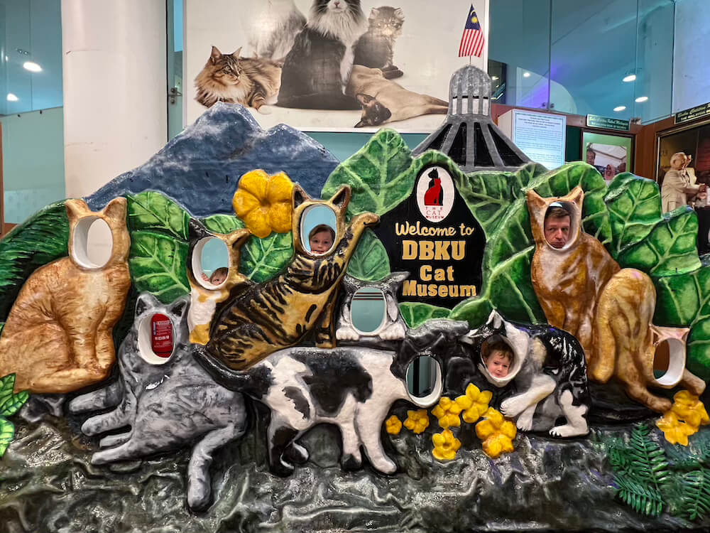 Interactive wooden cat display board with face cutouts inside the DBKU Cat Museum in Kuching.